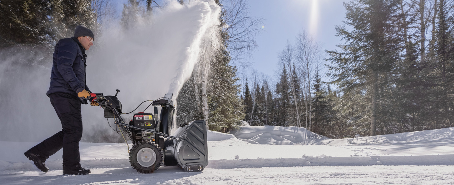 man clearing driveway with a snow blower